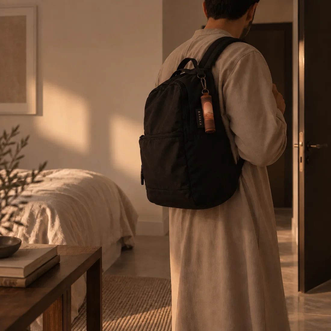 Homme s'apprêtant à sortir, le tapis nomade Baraka roulé et clipsé à son sac à dos
